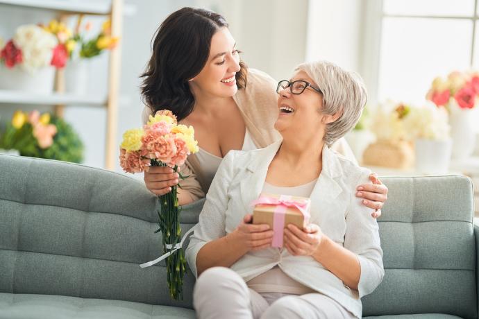 Dochter die haar moeder bloemen en een cadeautje geeft voor Moederdag