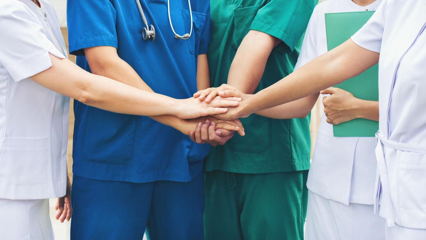Verpleegkundigen leggen hun handen samen
