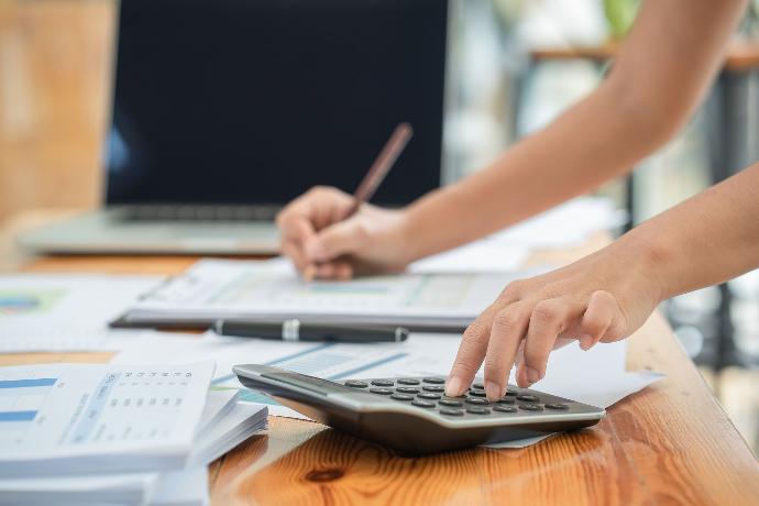 Persoon tikt op rekenmachine en schrijft tegelijkertijd op