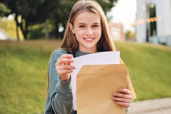 Meisje haalt witte brief uit bruine omslag.