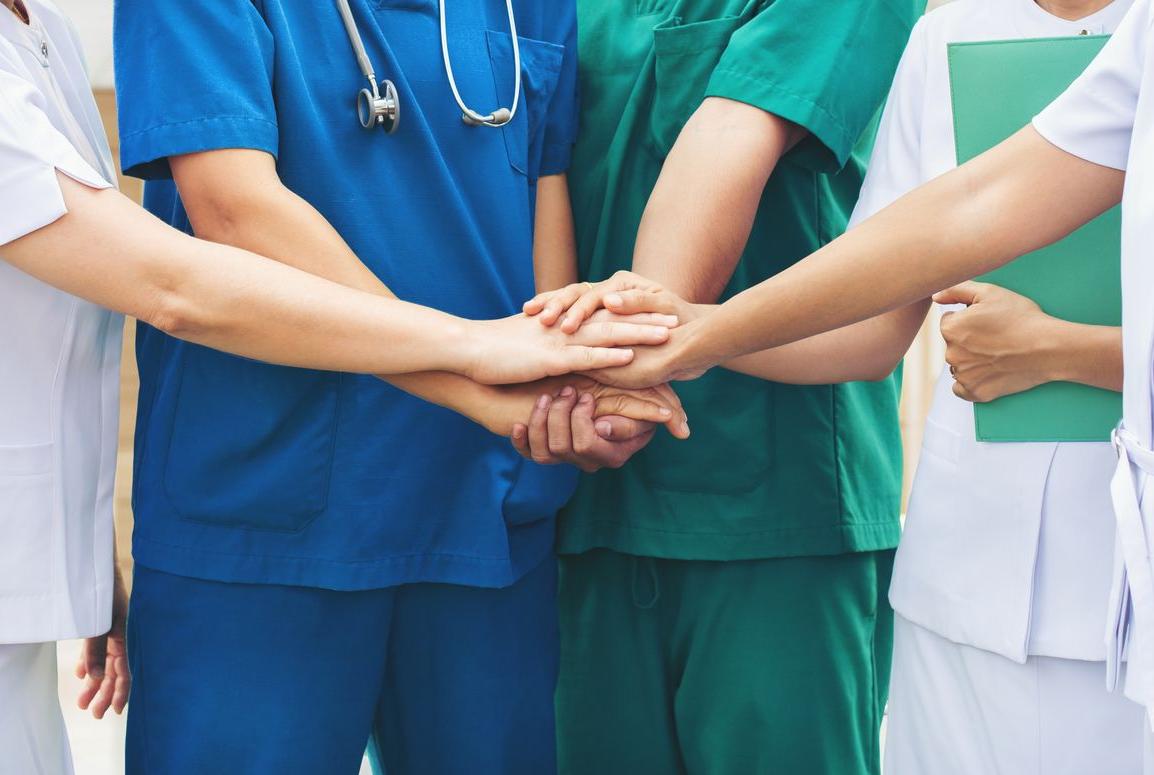 Verpleegkundigen leggen hun handen samen
