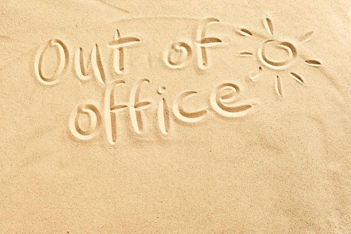 Out of office geschreven in het zand